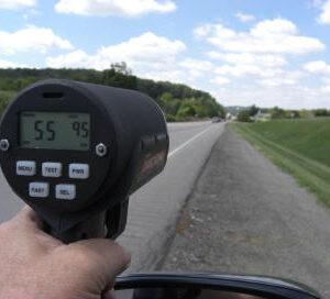 A person is holding up a speed gun to check the speed of their car.