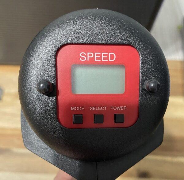 A red and black speed meter on top of a wooden table.